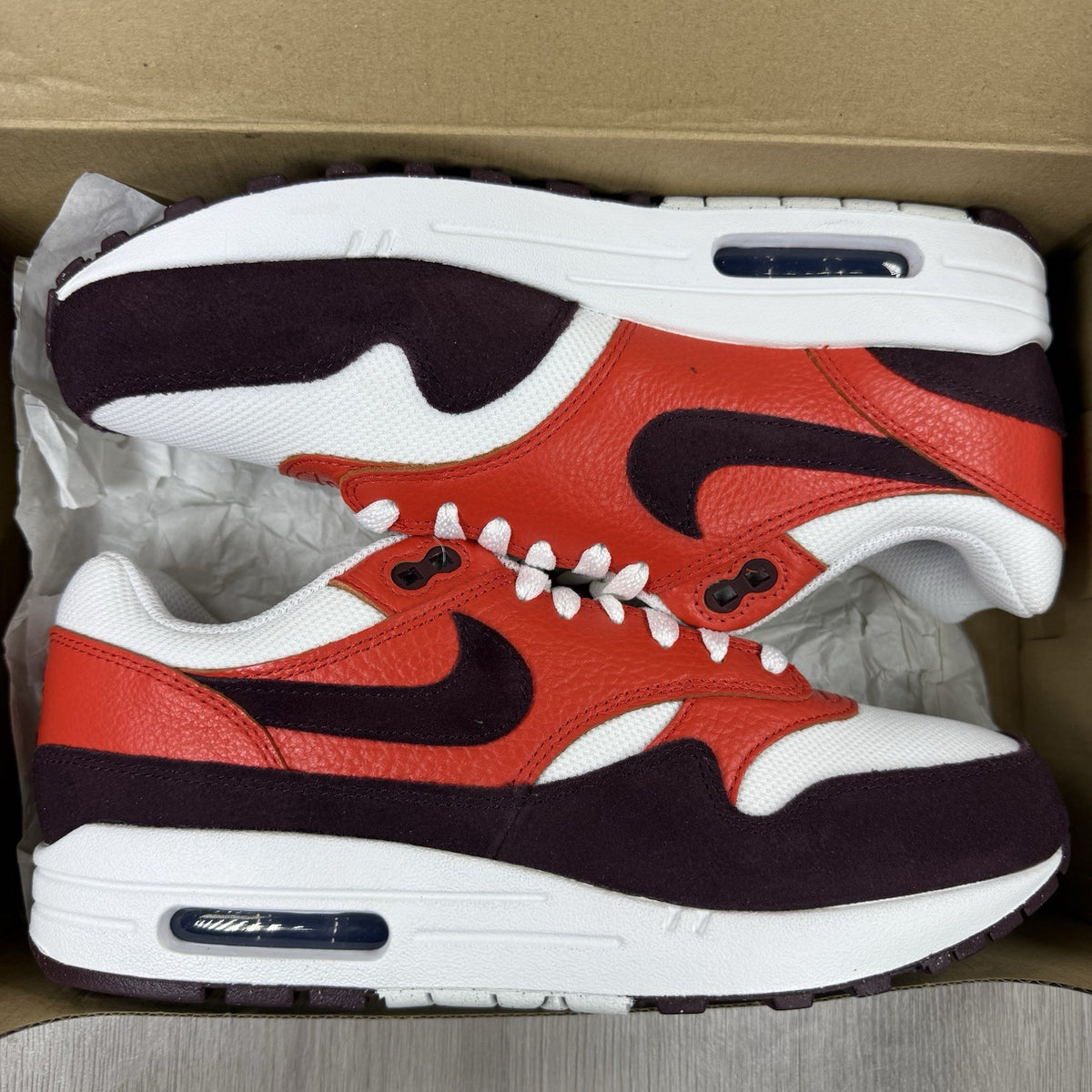Nike Air Max 1 red trainers with white accents and signature swoosh logo.