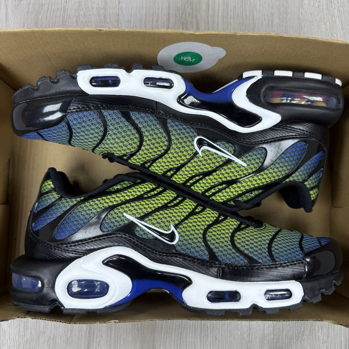 Nike Air Max Plus TN trainers black with racer blue and volt accents, mesh material.