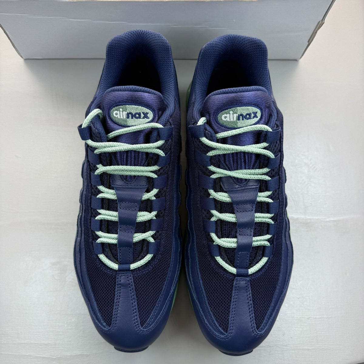 Nike Air Max 95 navy blue trainers with green accents and classic logo detailing.