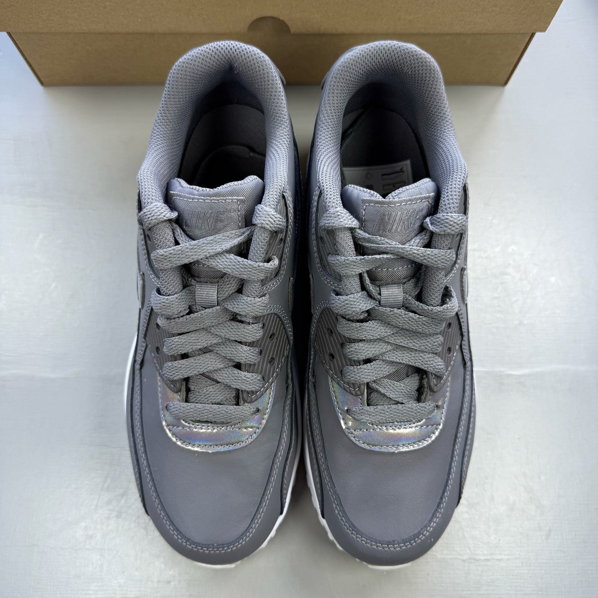 Nike Air Max 90 grey trainers with white accents and logo detail.