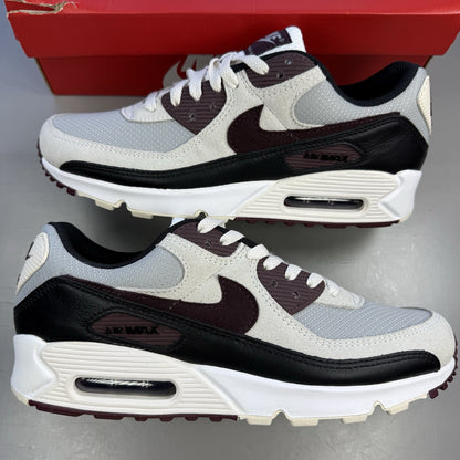 Nike Air Max 90 grey trainers with burgundy accents and black detailing.