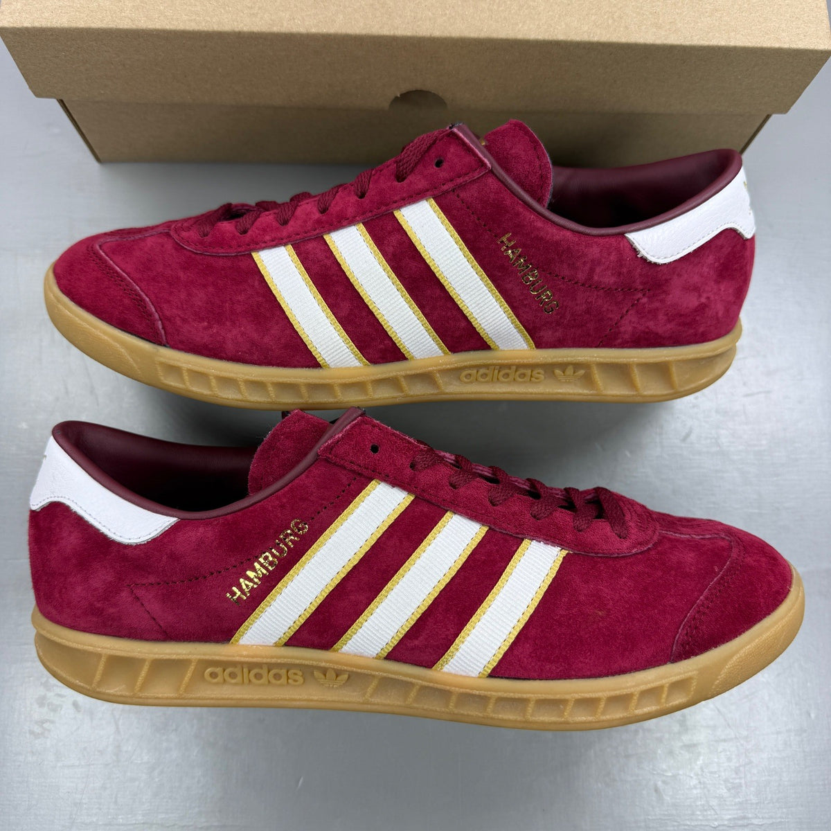 Adidas red athletic shoes with white stripes and gum sole, size UK 7.5.