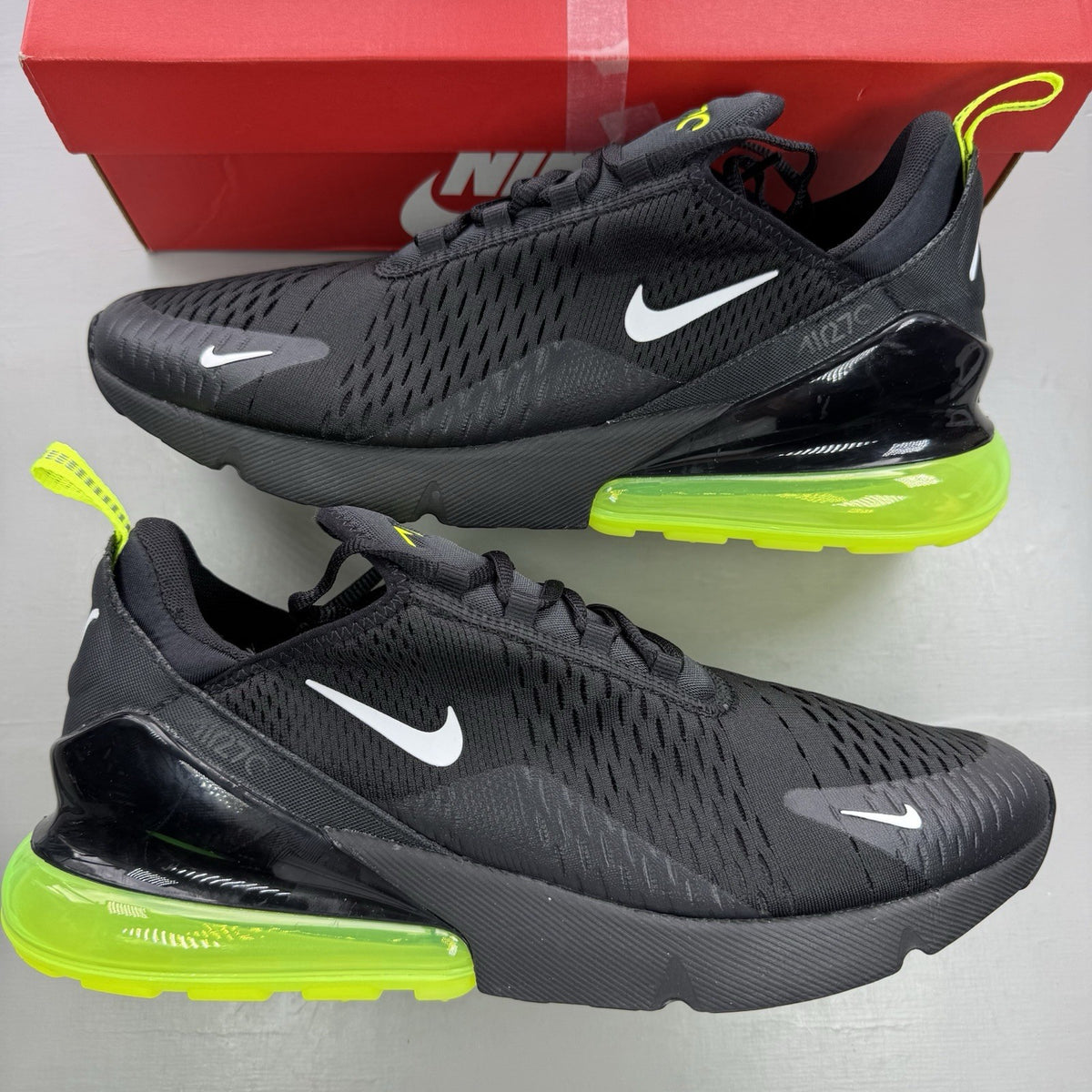 Nike Air Max 270 black trainers with neon volt accents and white sole.