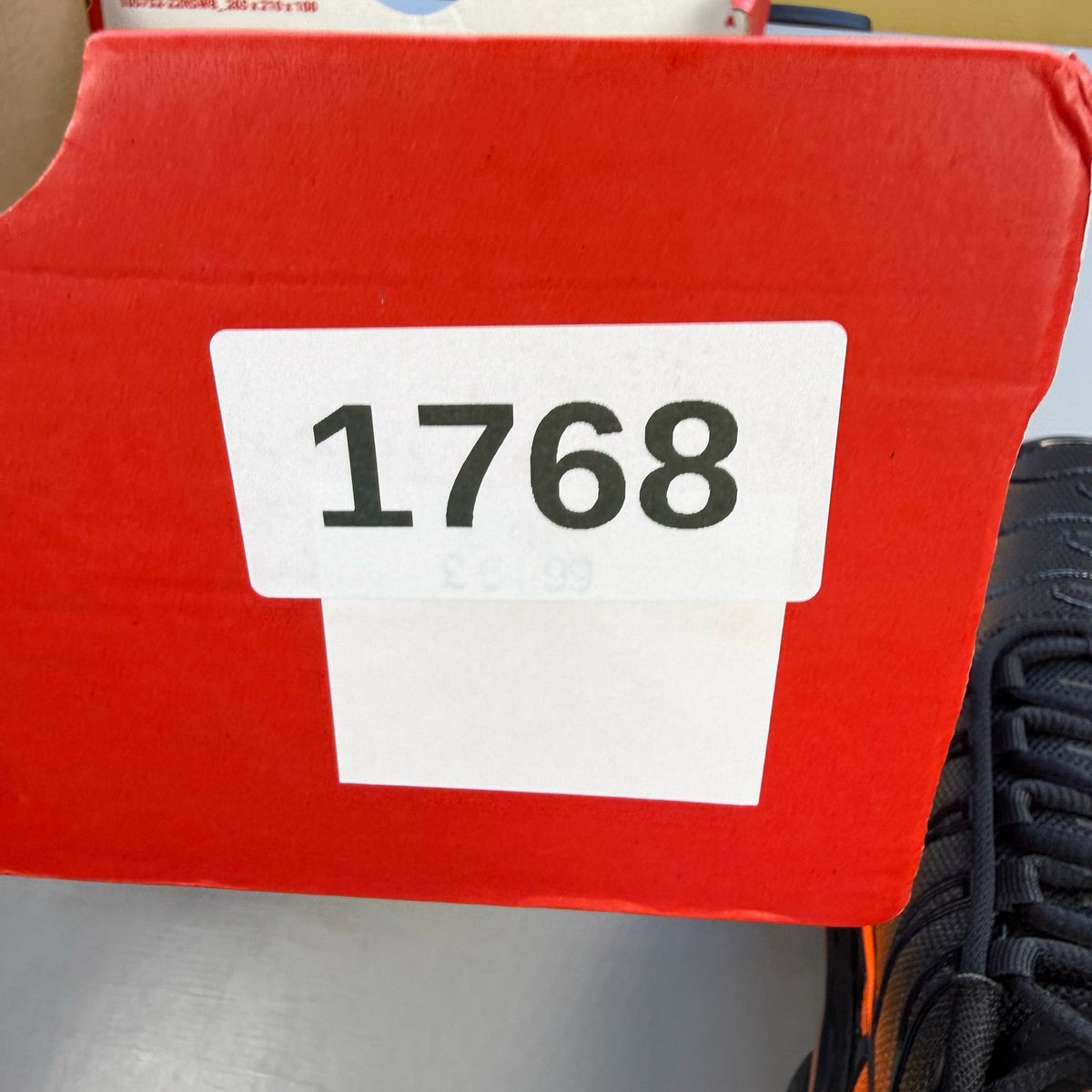 Nike Air Max Plus TN black trainers with orange accents and signature logo details.