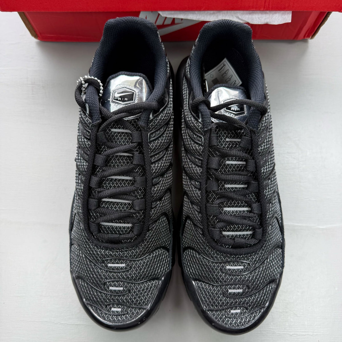 Nike black trainers suede material with silver accents and iconic Air Max Plus design.