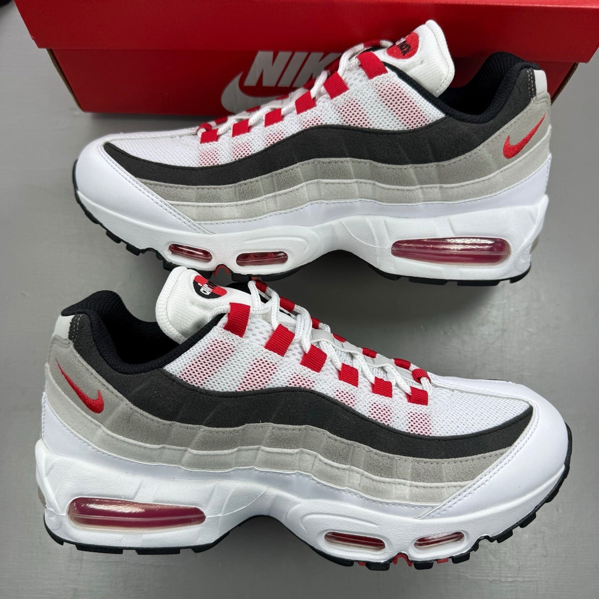 Nike trainers white with red accents and iconic Air Max bubble sole.