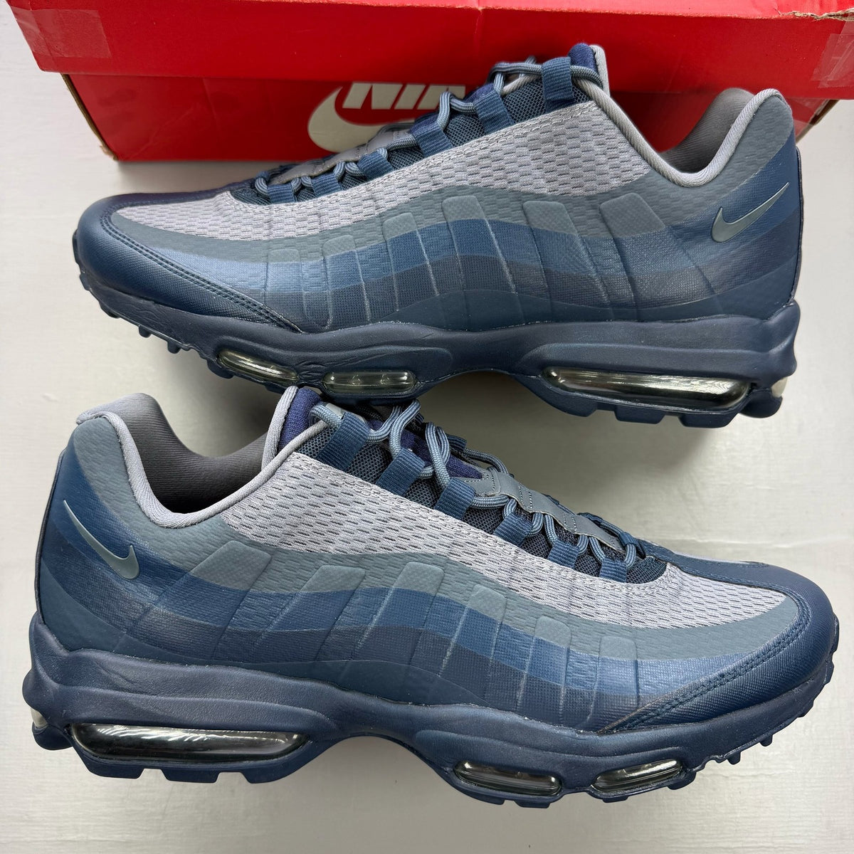 Nike Air Max 95 blue trainers with mesh upper and rubber sole, featuring logo detail.