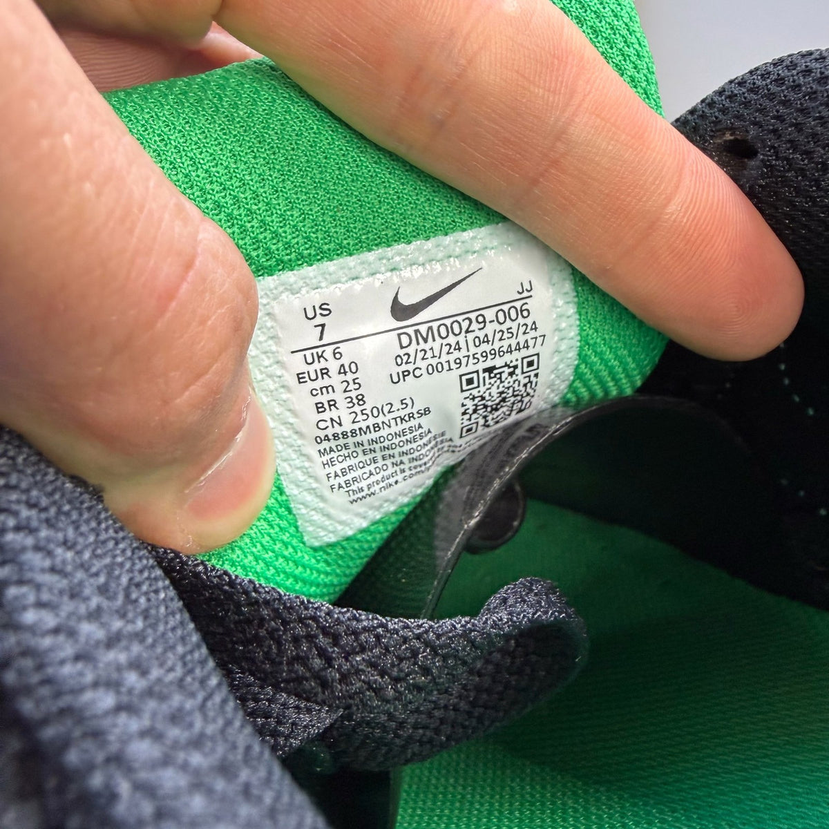 Nike Air Max 90 black trainers with green accents and white sole, featuring logo details.