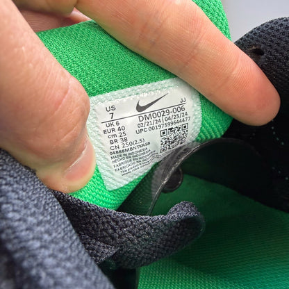 Nike Air Max 90 black trainers with green accents and white sole, featuring logo details.