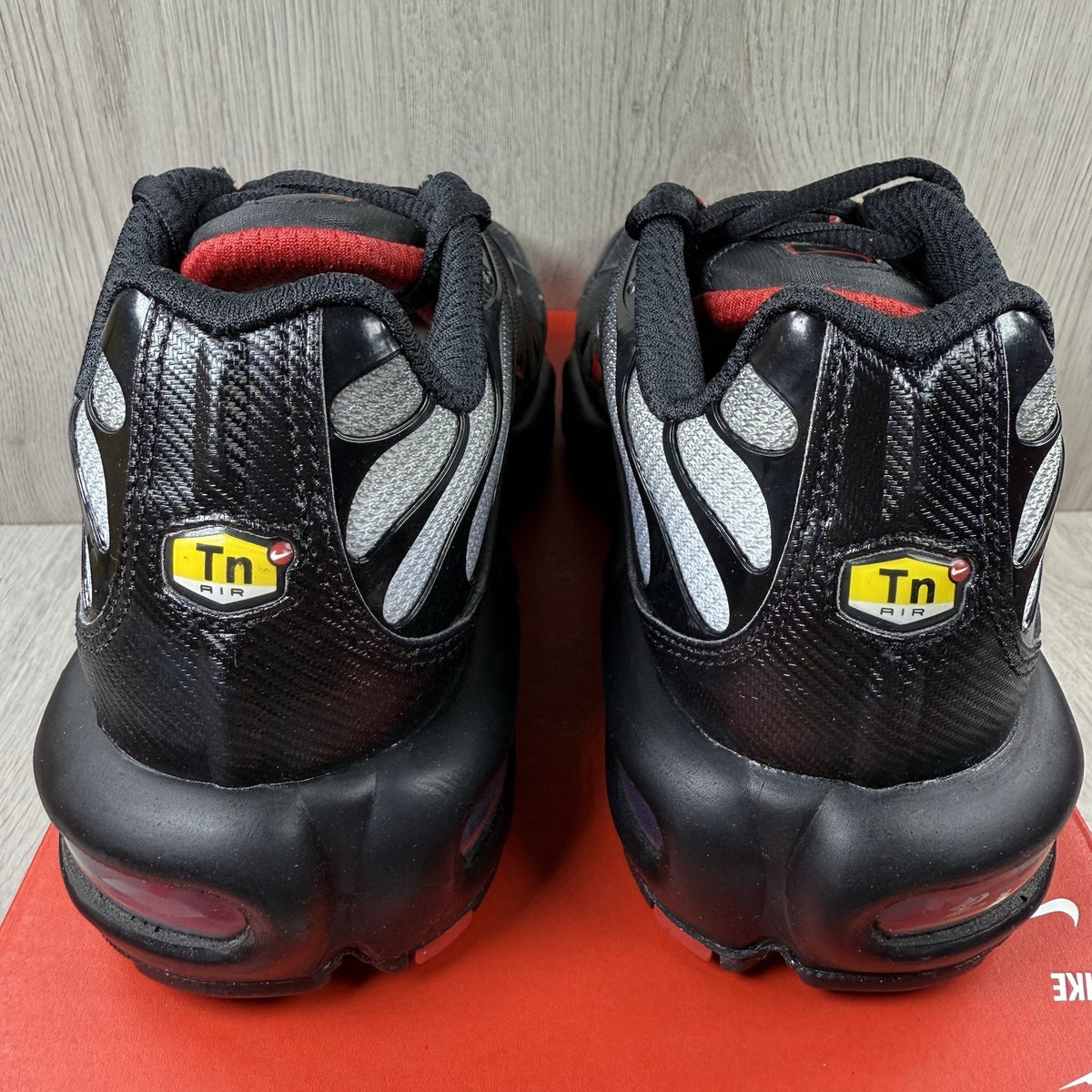Nike TN Air Max Plus trainers black with red gradient and signature logo design.