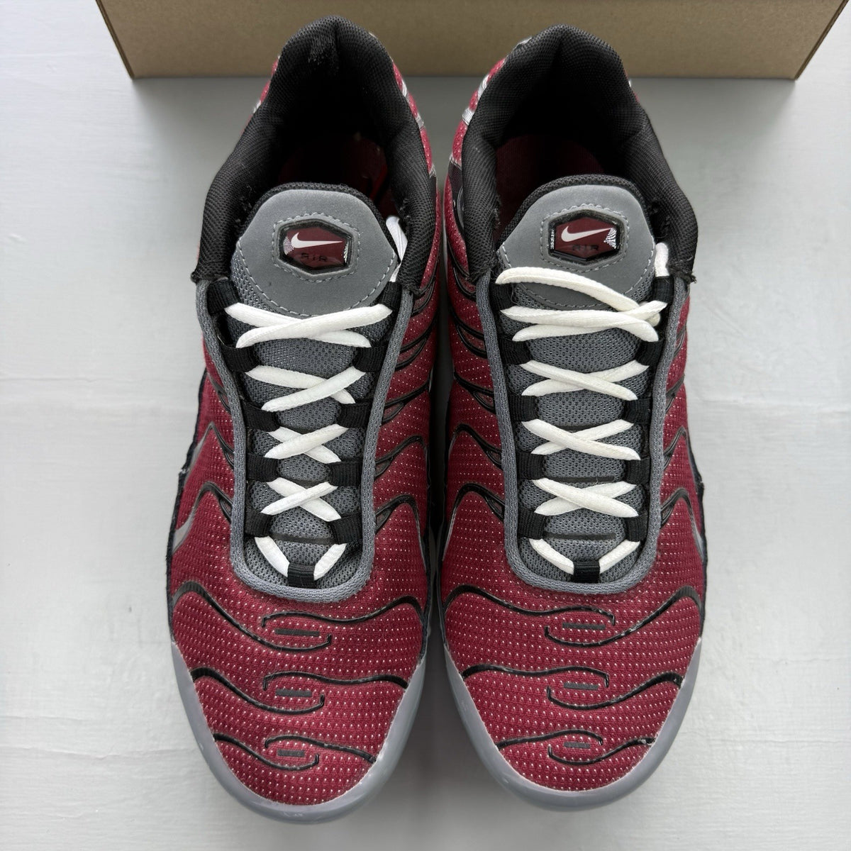 Nike Air Max Plus TN white trainers with red and black accents, featuring logo detailing.