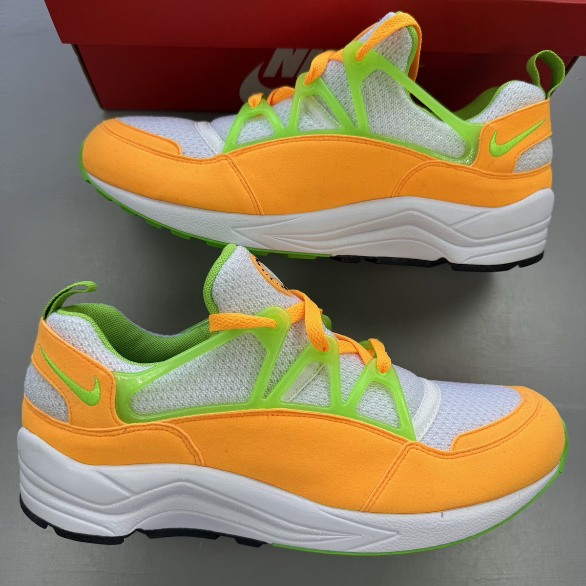 Nike Air Huarache Light white trainers with atomic mango accents and green details.
