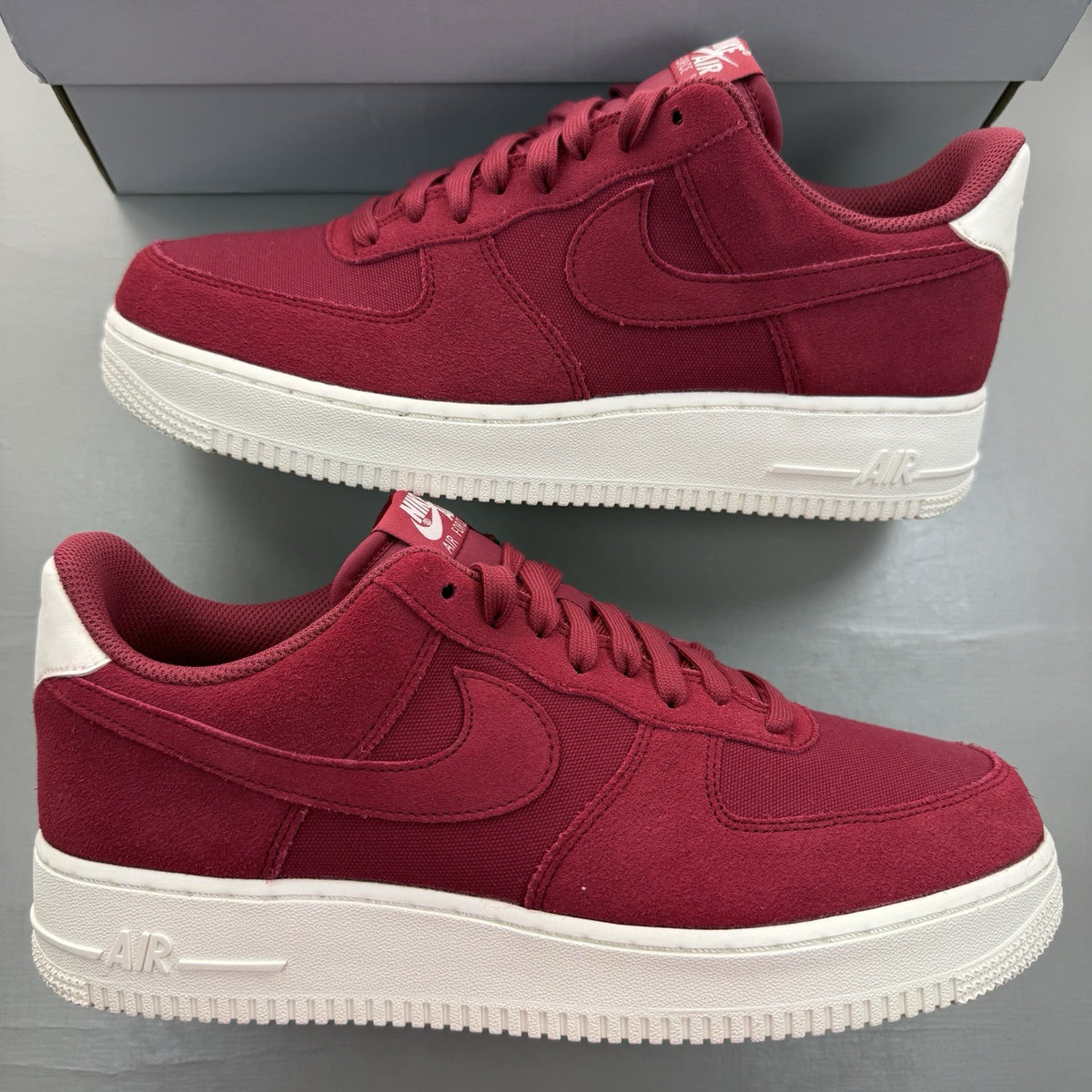 Nike Air Force 1 trainers red suede with white accents and logo detail.