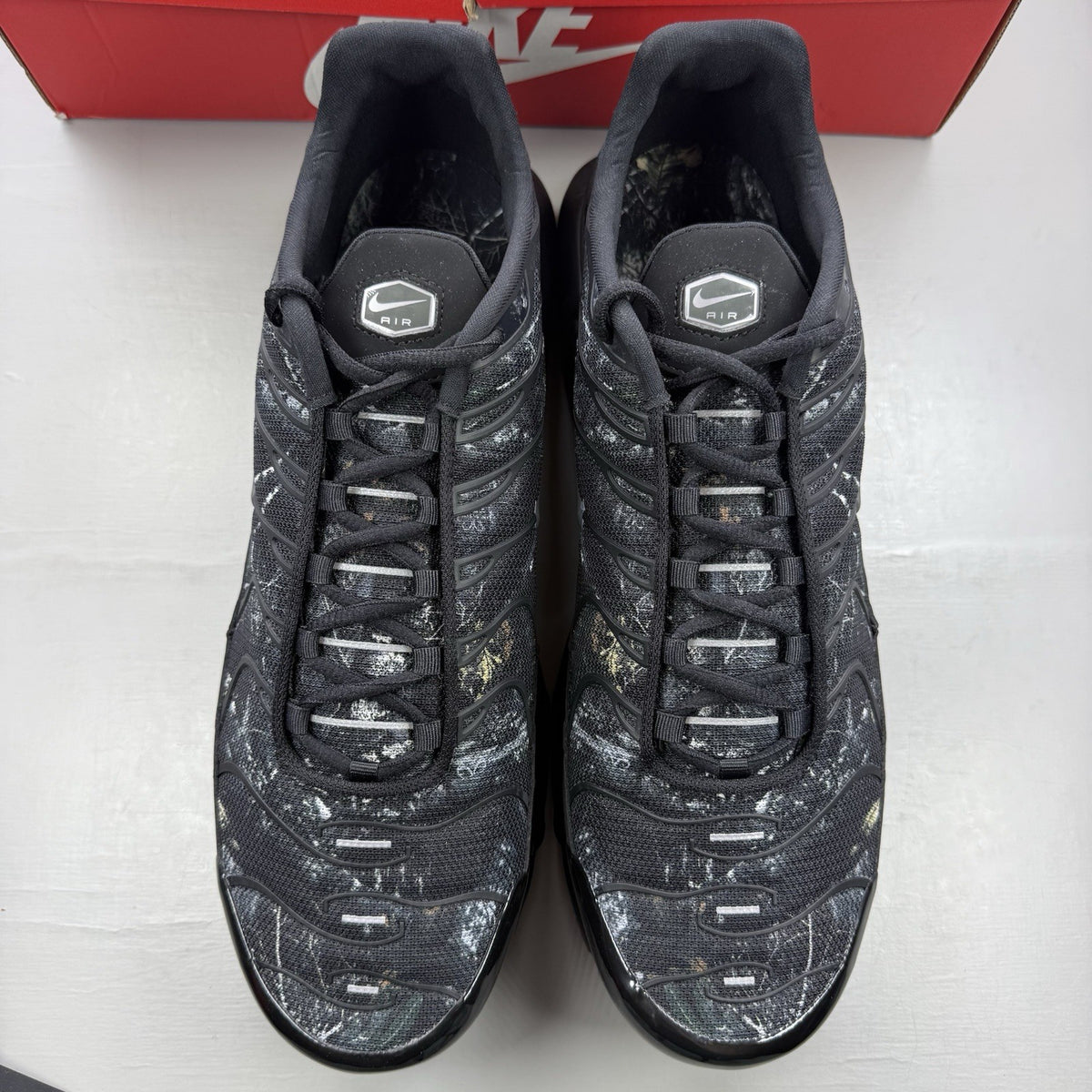 Nike black trainers featuring wood camo pattern and Air Max Plus design.