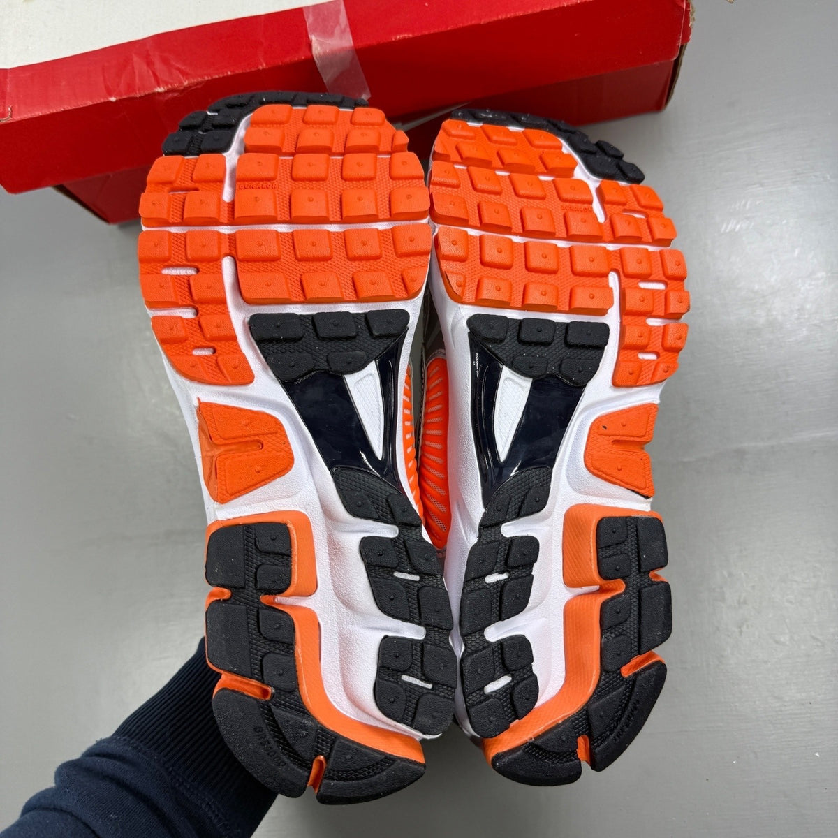 Nike running shoes orange with grey accents and distinctive logo detailing.