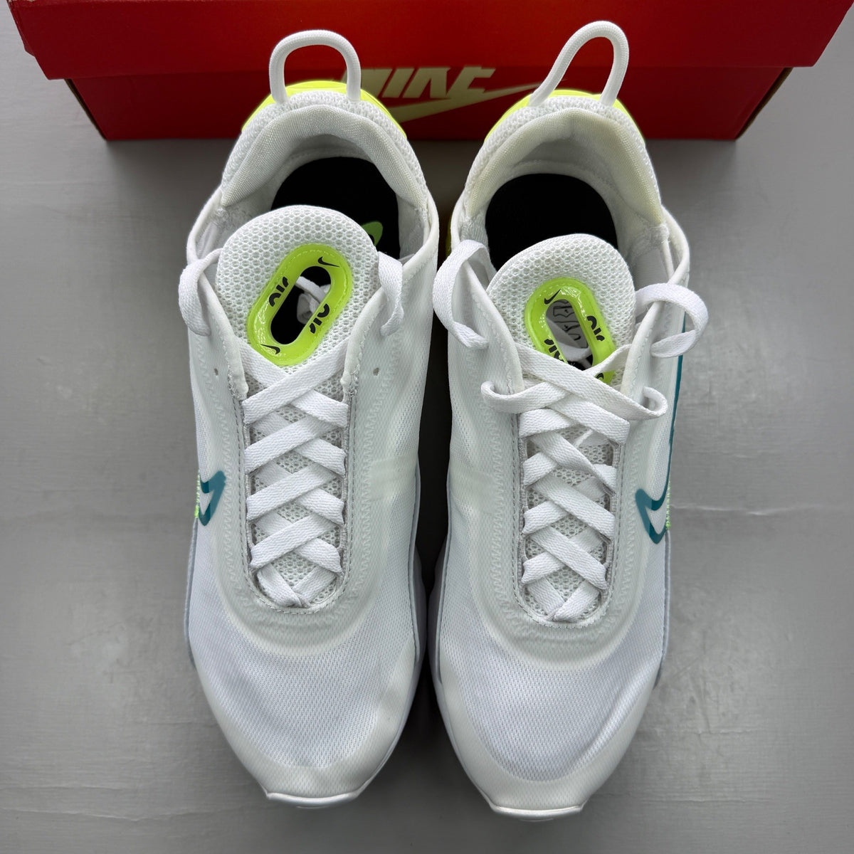 Nike white trainers with aquamarine and lime glow accents, featuring iconic logo details.