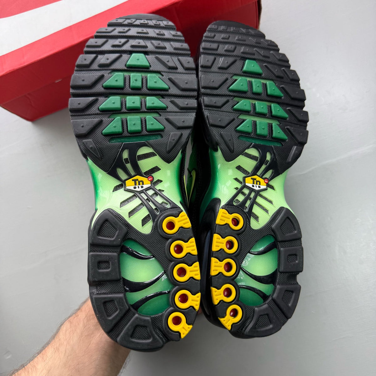 Nike Air Max Plus TN green trainers with lemon twist accents and signature logo.