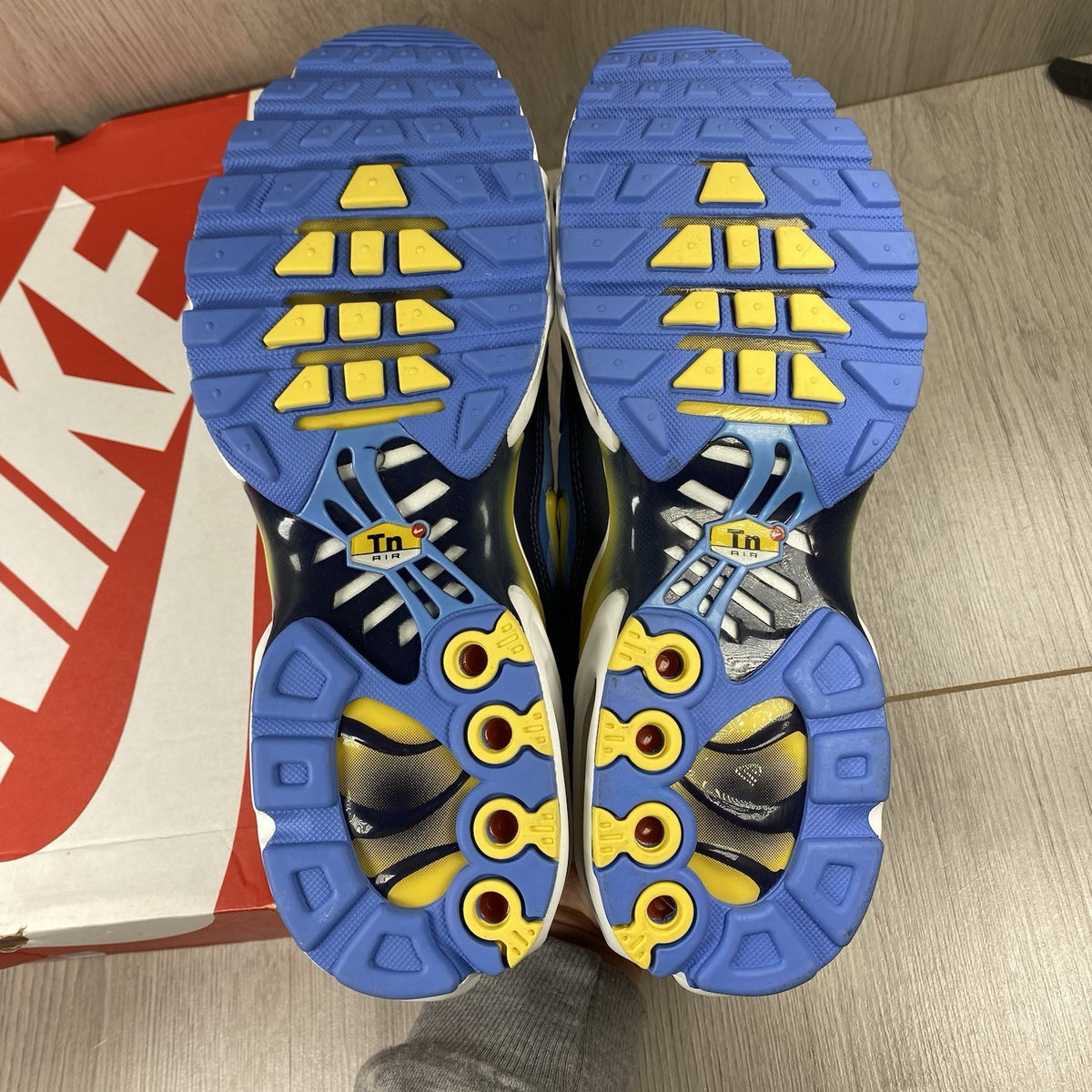 Nike Air Max Plus TN blue trainers with yellow accents and signature swoosh logo.