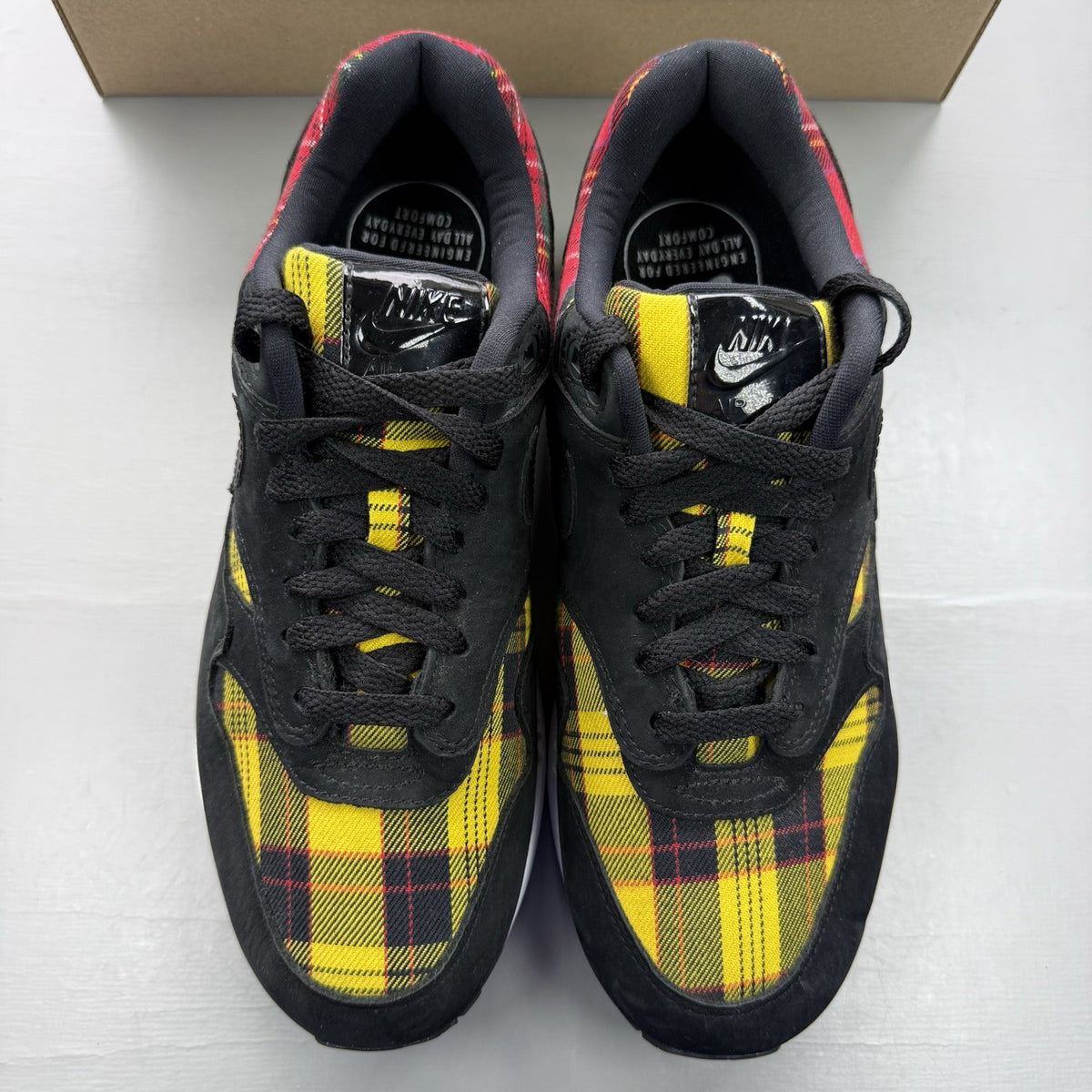 Nike Air Max 1 SE trainers black with tartan pattern and yellow accents.