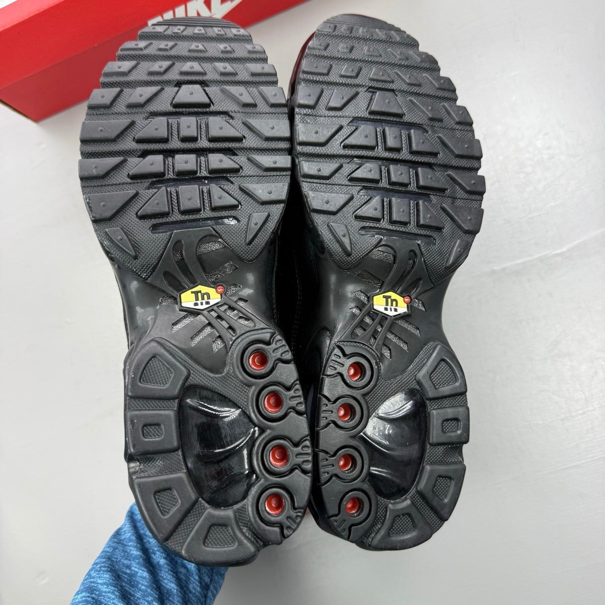 Nike Air Max Plus TN black leather trainers with distinctive wave pattern and logo.