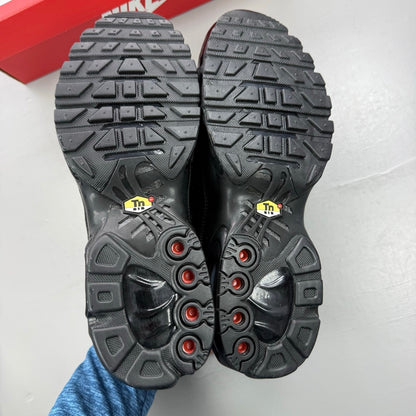 Nike Air Max Plus TN black leather trainers with distinctive wave pattern and logo.