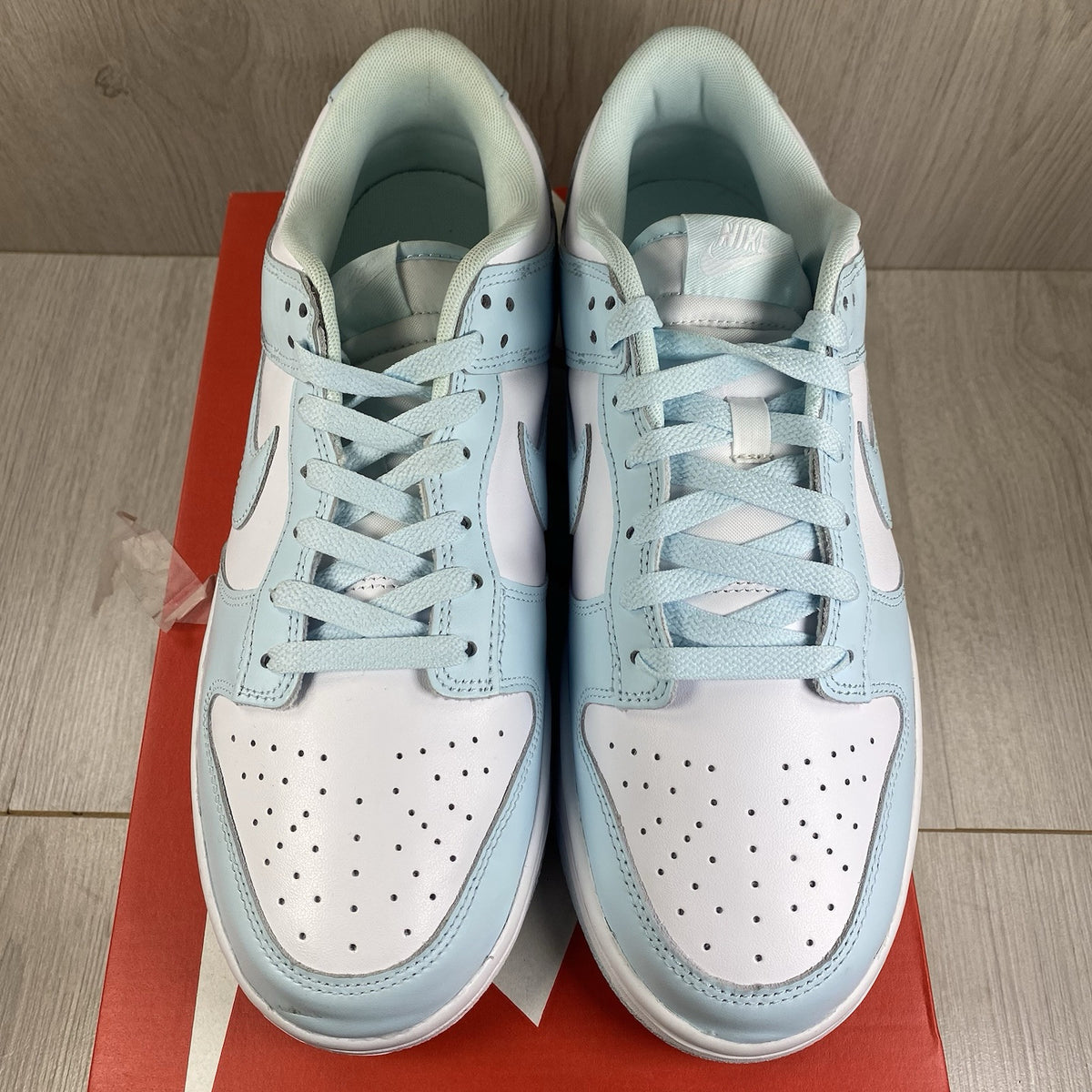 Nike Dunk Low Retro trainers glacier blue with white swoosh logo and textured material.