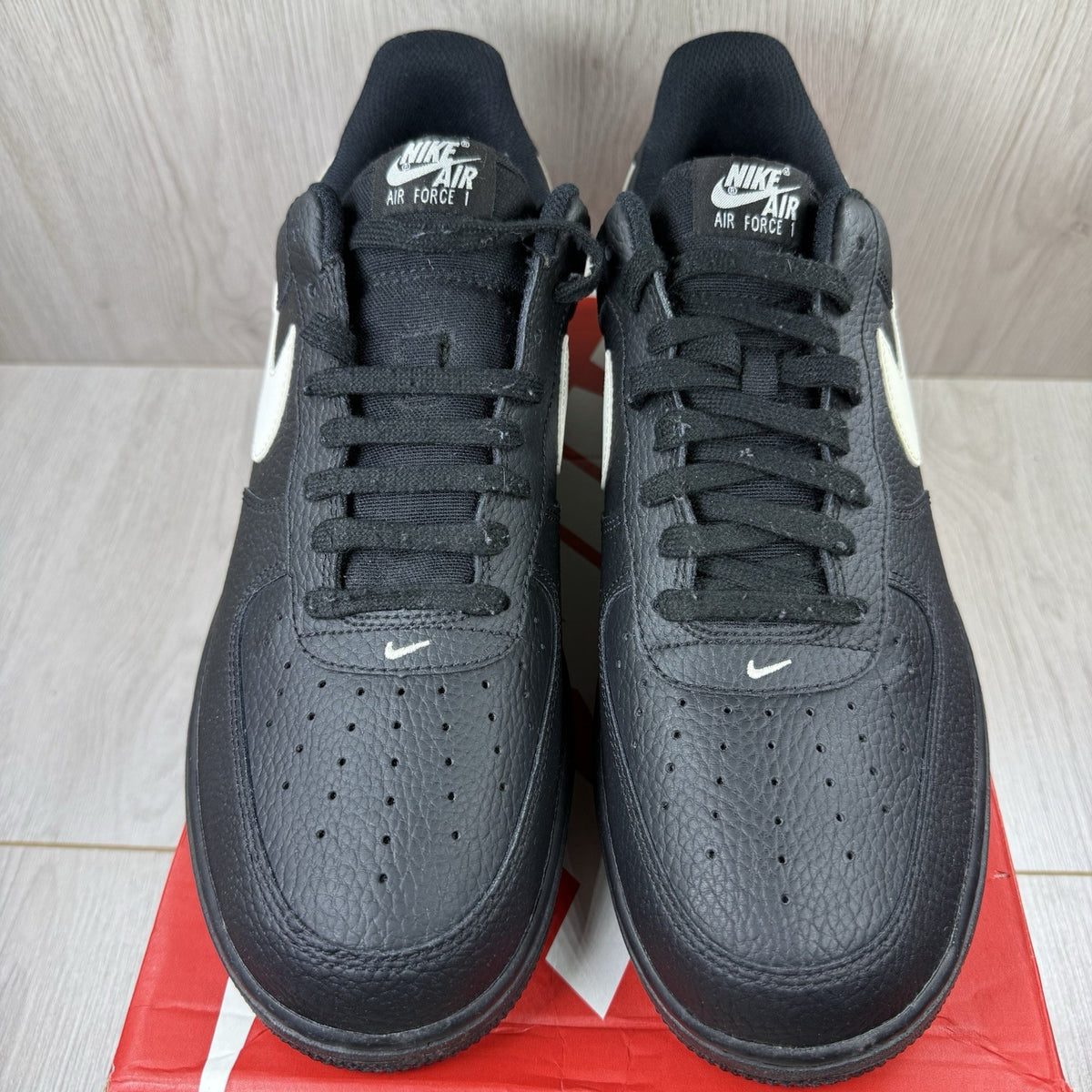 Nike Air Force 1 Low trainers black with white swoosh logo and sail accents.