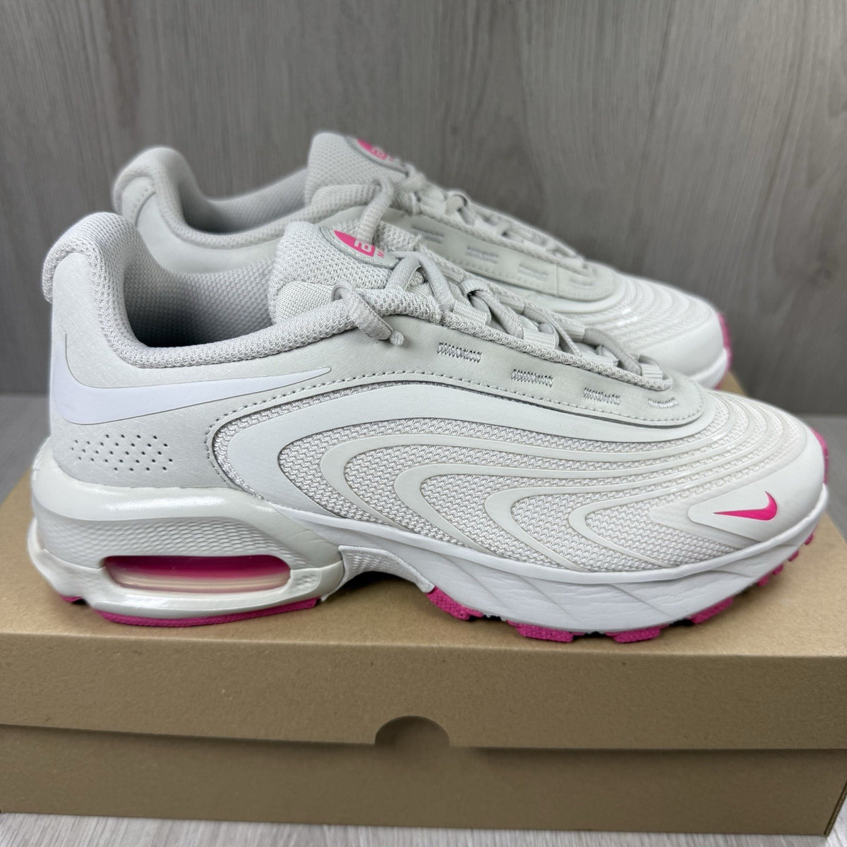 Nike Air Max trainers beige with pink accents and logo detail on the side.