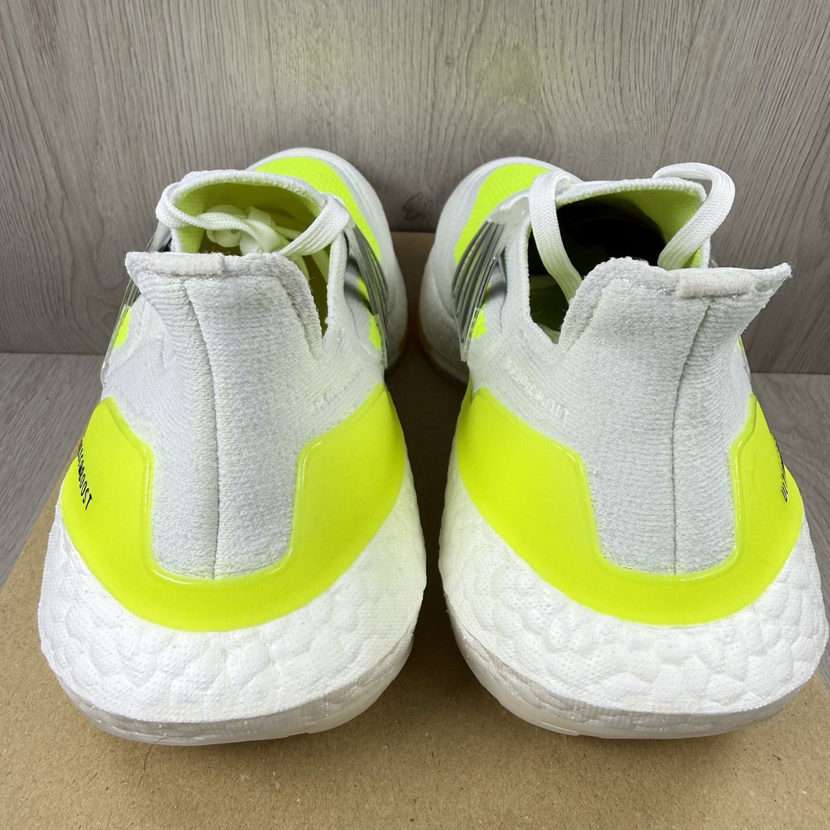 Adidas Ultra Boost 21 white trainers with solar yellow accents and signature three-stripe logo.