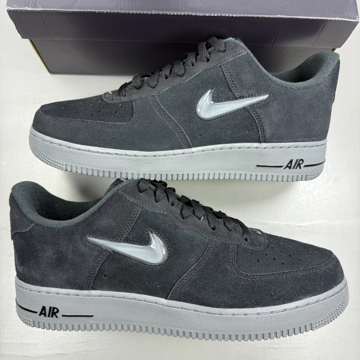 Nike Air Force 1 black trainers with cool grey accents and jewel detailing.
