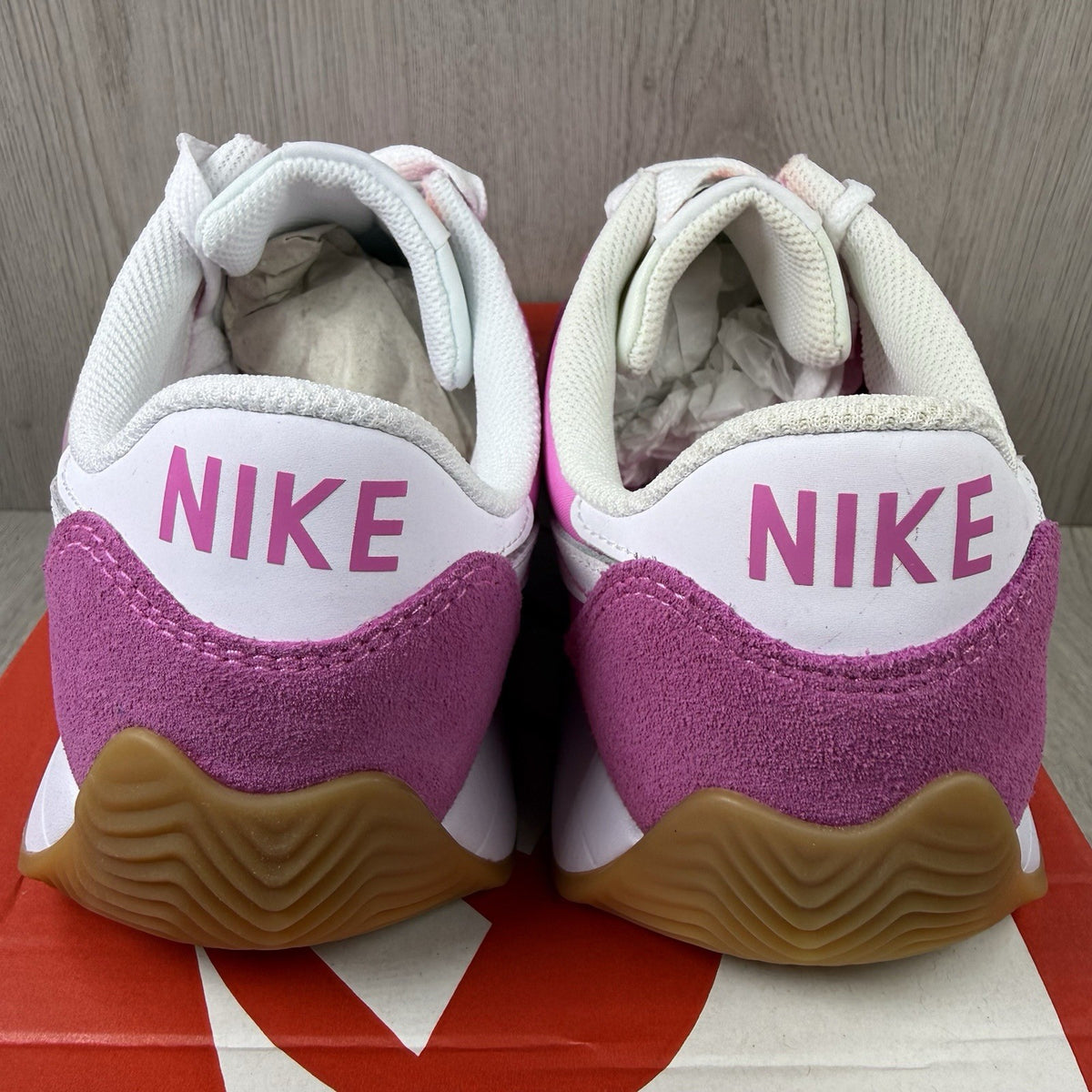 Nike white trainers with pink accents and gum sole, featuring iconic swoosh logo.