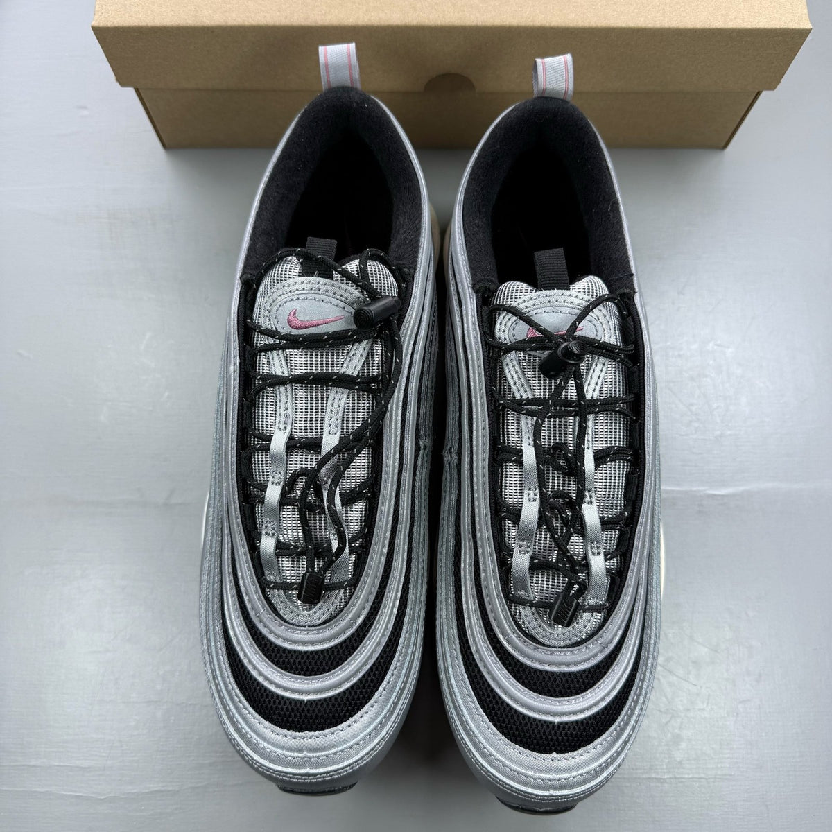 Nike Air Max 97 metallic silver trainers with berry accents and signature swoosh logo.
