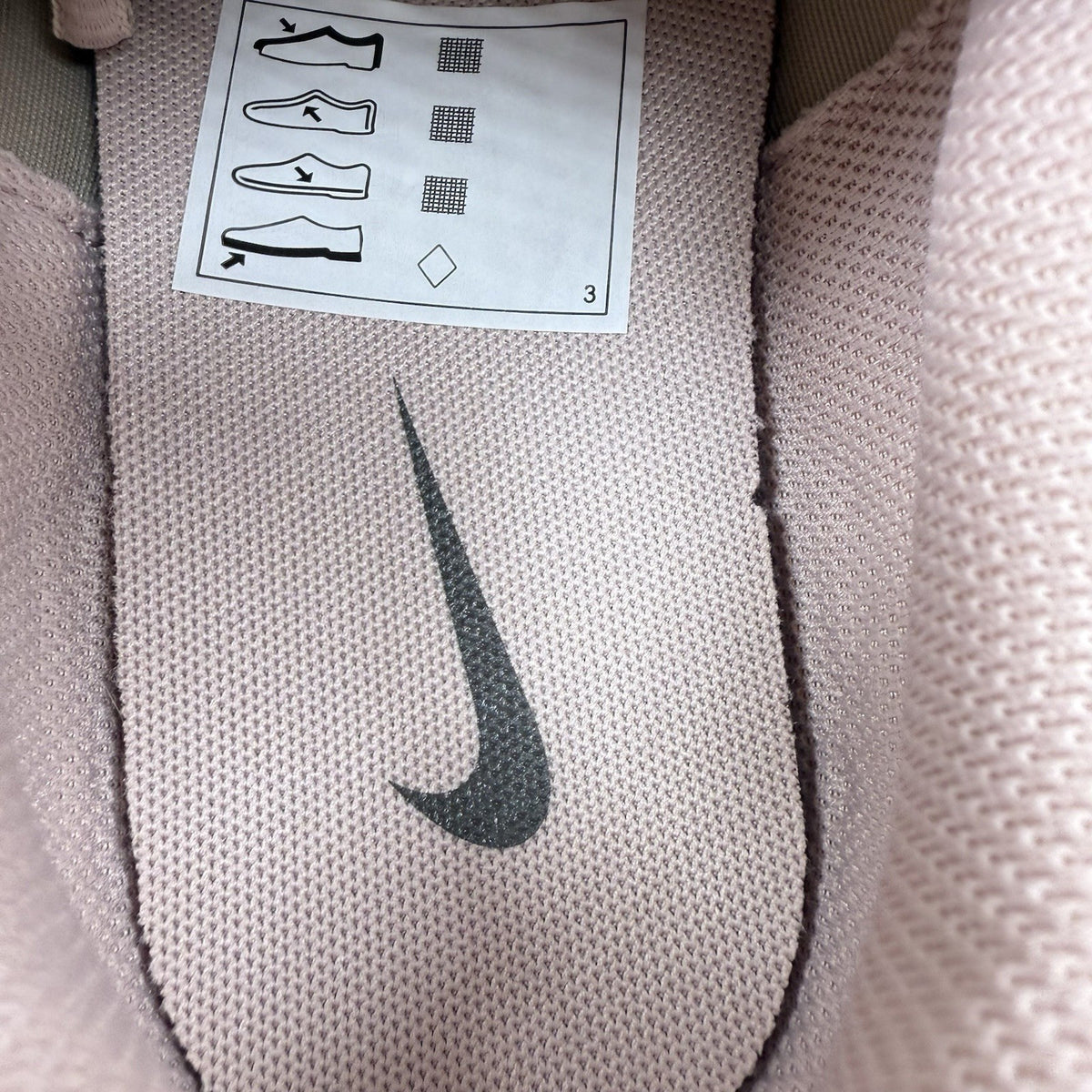 Nike beige trainers with pink accents and mesh detailing, featuring iconic swoosh logo.