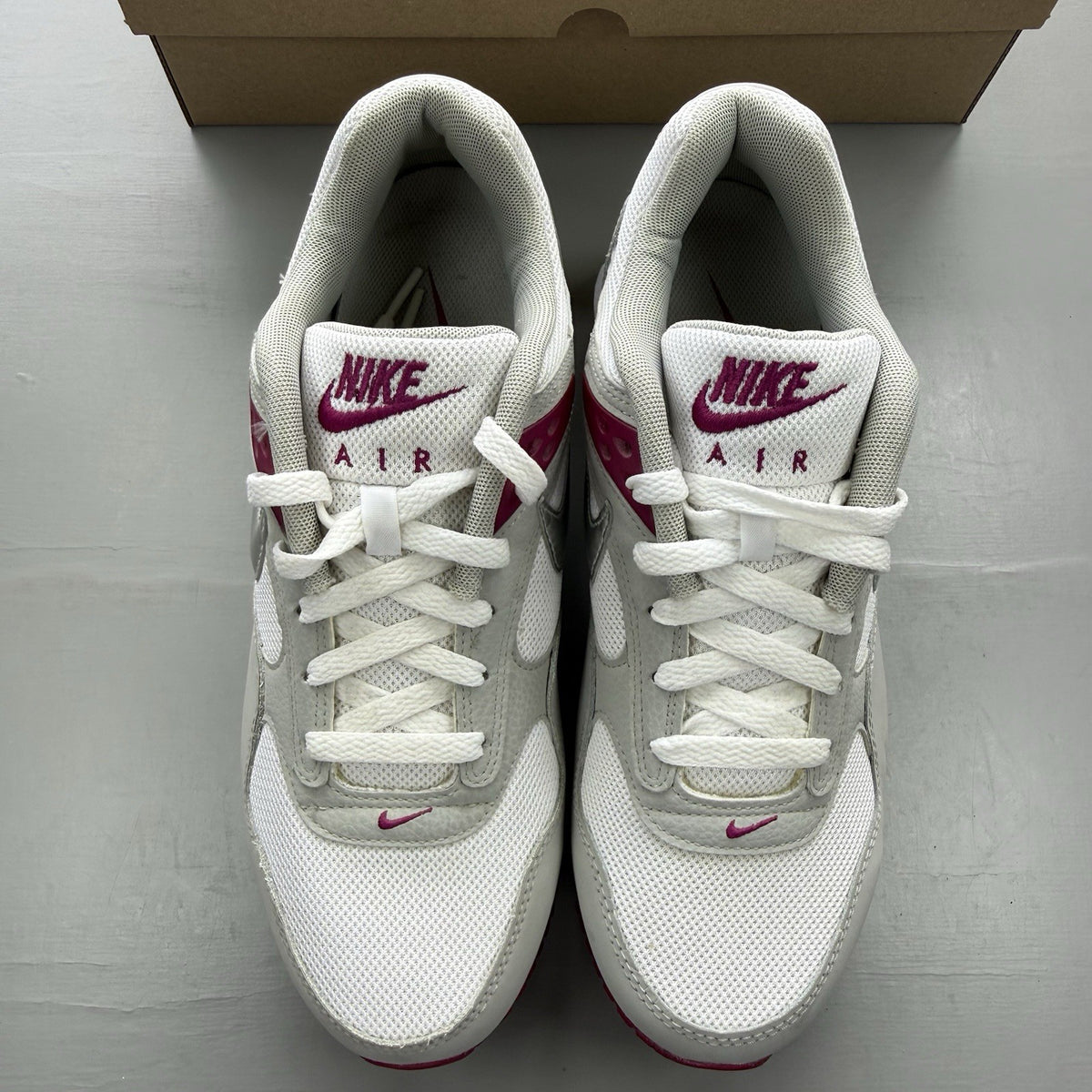 Nike Air Max Correlate white trainers with fuchsia accents and logo detailing.