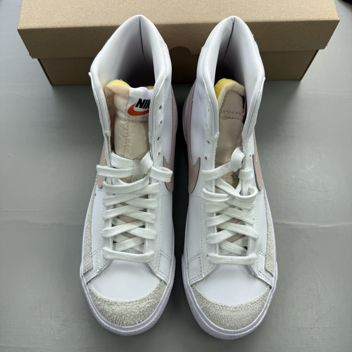 Nike Blazer Mid 77 white trainers with pink accents and retro logo design.