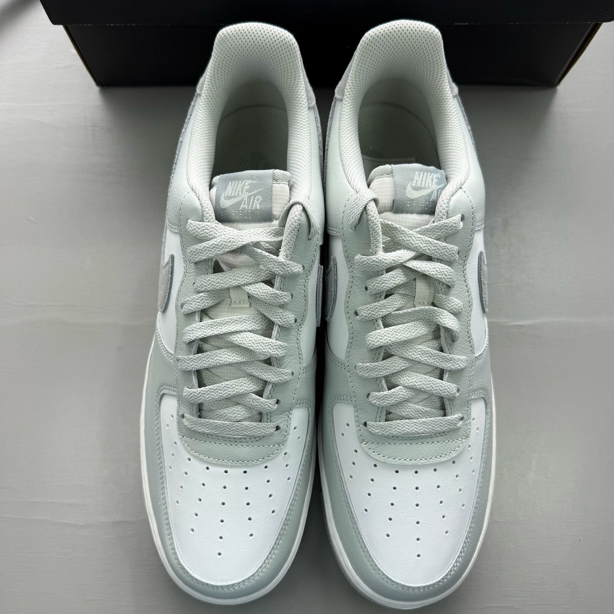 Nike Air Force 1 grey low-top sneakers with light silver accents and white sole.