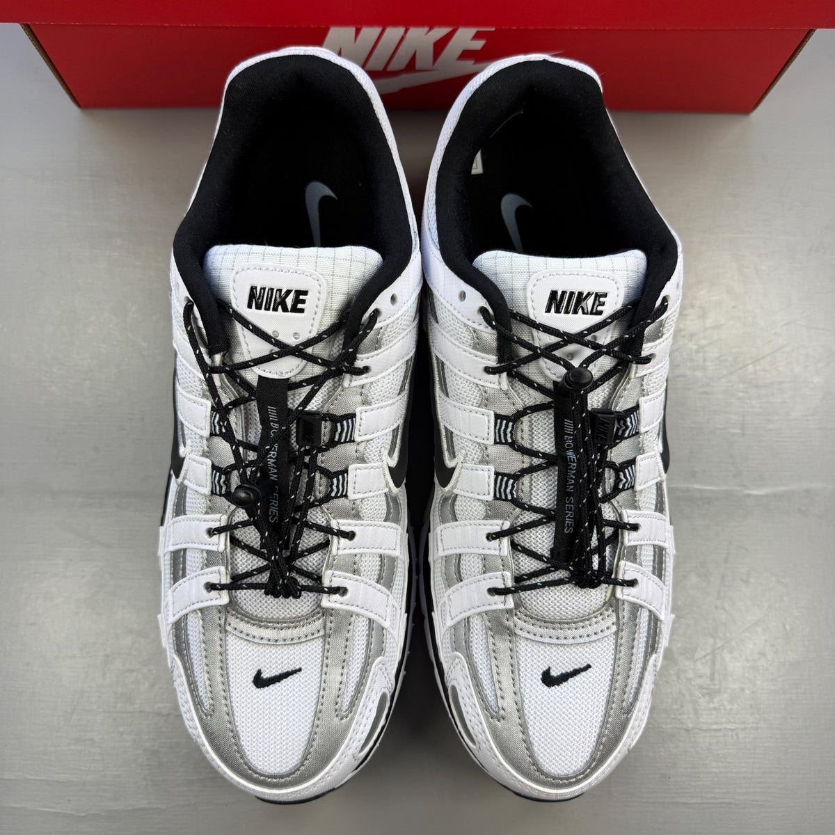 Nike white trainers with light armoury blue and black accents, featuring logo details.