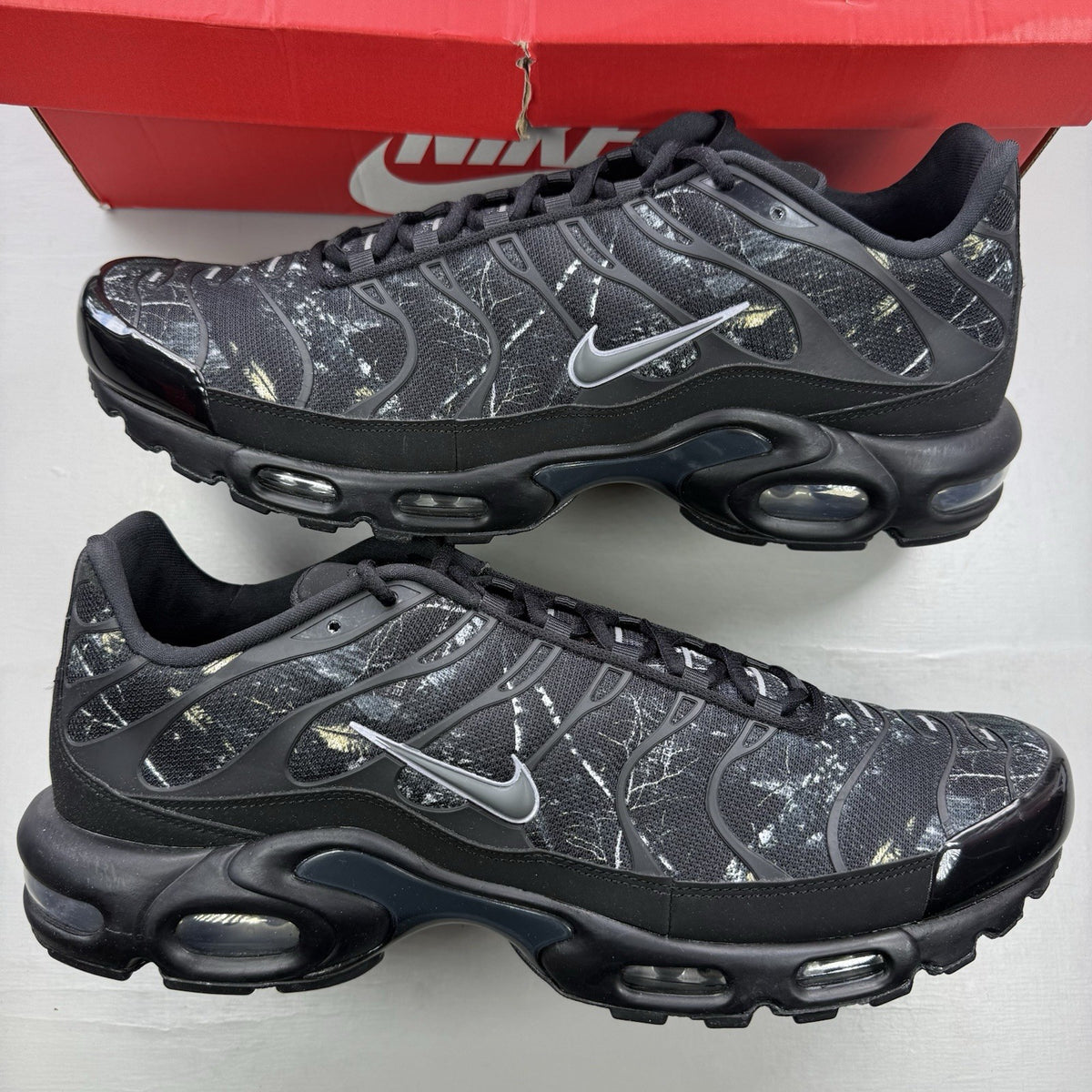 Nike black trainers featuring wood camo pattern and Air Max Plus design.