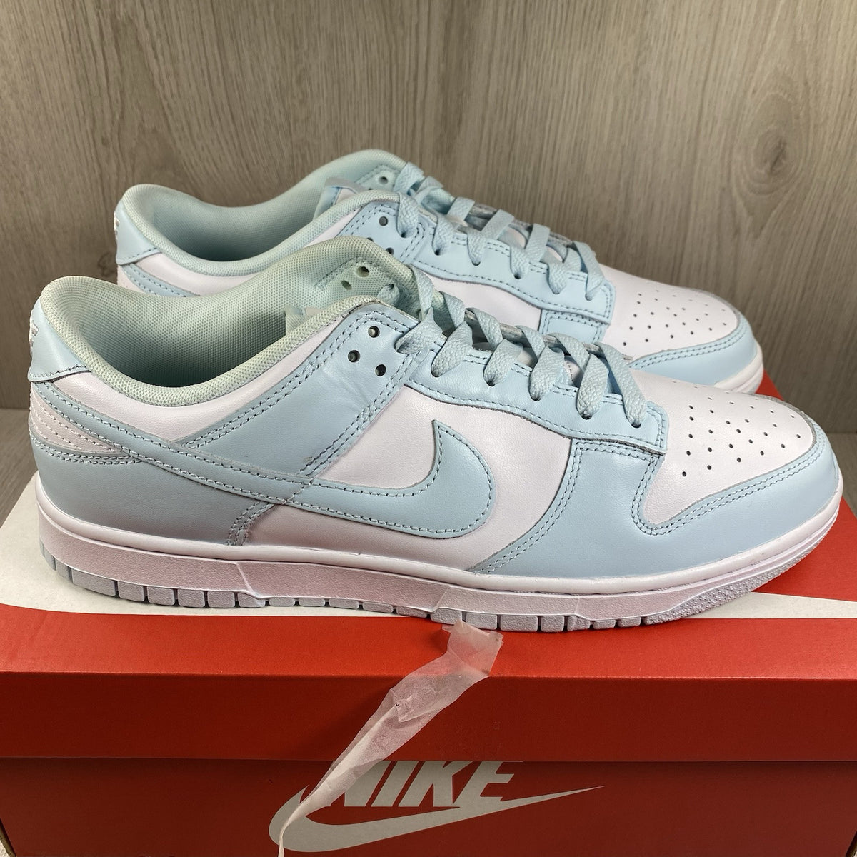 Nike Dunk Low Retro trainers glacier blue with white swoosh logo and textured material.