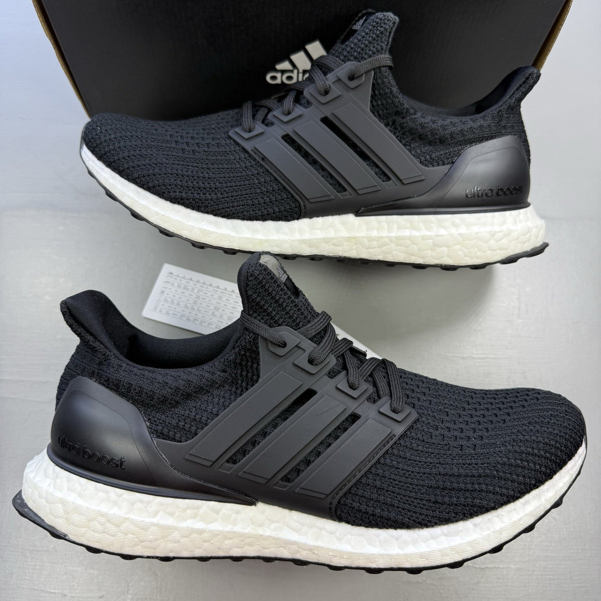 Adidas black Ultra Boost trainers with white accents and signature three-stripe logo.