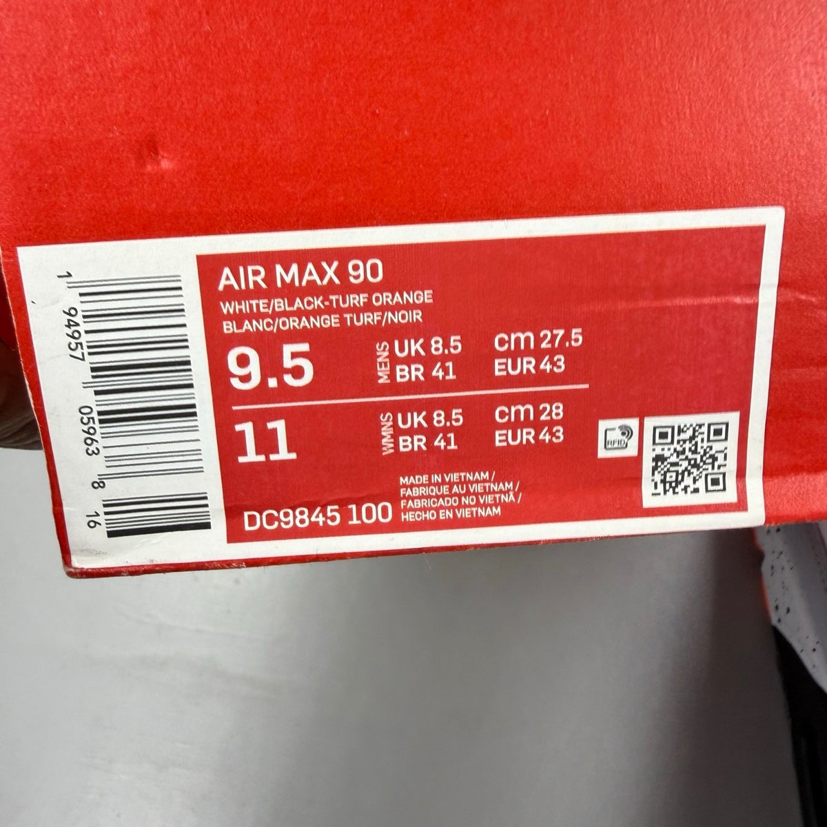 Nike Air Max 90 black trainers with turf orange and white accents, featuring logo details.