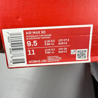 Nike Air Max 90 black trainers with turf orange and white accents, featuring logo details.