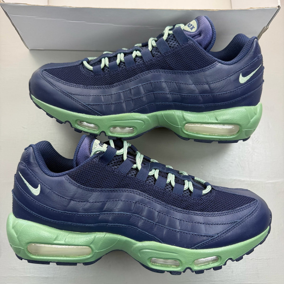 Nike Air Max 95 navy blue trainers with green accents and classic logo detailing.