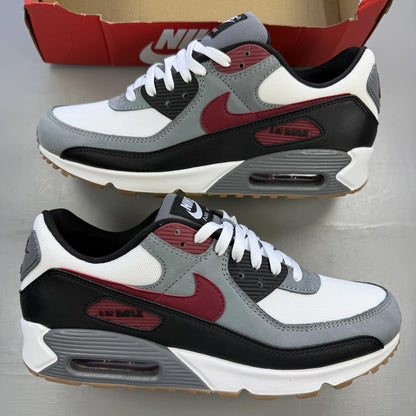 Nike Air Max 90 grey trainers with red accents and gum sole, featuring logo details.