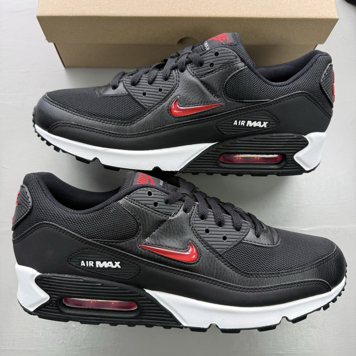 Nike Air Max 90 Jewel trainers black with red and white accents, featuring iconic logo.