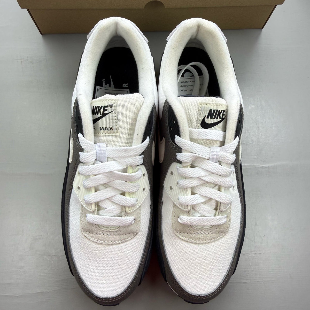 Nike Air Max 90 white trainers with obsidian and pewter accents, featuring logo detail.