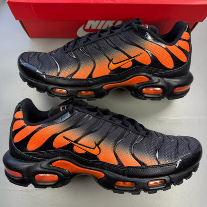 Nike Air Max Plus TN black trainers with total orange accents and signature logo.
