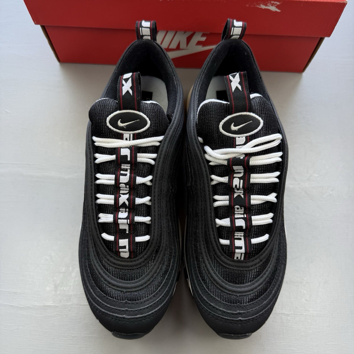 Nike Air Max 97 SE black trainers with white and varsity red accents, mesh and leather material.