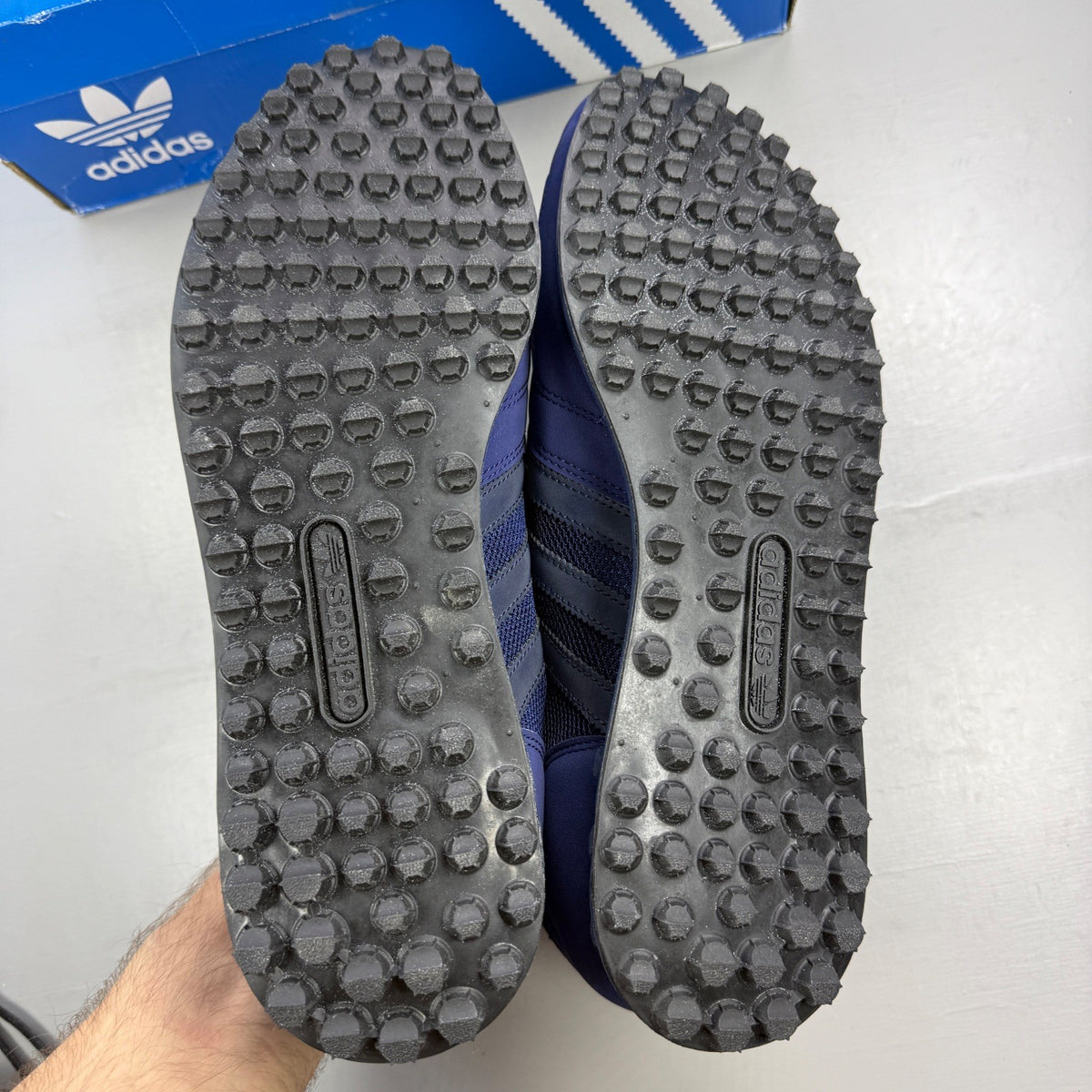 Adidas blue trainers with black accents and signature three-stripe logo.