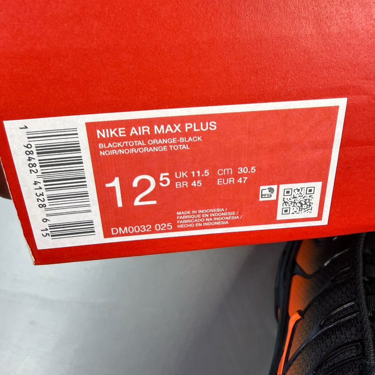Nike Air Max Plus TN black trainers with total orange accents and signature logo.
